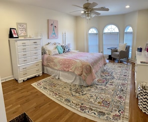 A bedroom with a bed, dresser, and a large rug.