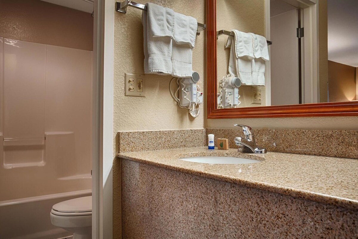 A bathroom with a granite countertop, a sink, a mirror, and a towel rack.