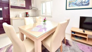 Une cuisine moderne avec un coin repas, un téléviseur à écran plat et un tableau accroché au mur.