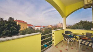 Un balcon jaune avec une table et des chaises, donnant sur un quartier résidentiel.