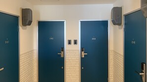 A row of four blue doors with numbers 201, 202, 203, and 204, each with a handle and a lock. - Ecot Kugai 1 (Miyakojima)
