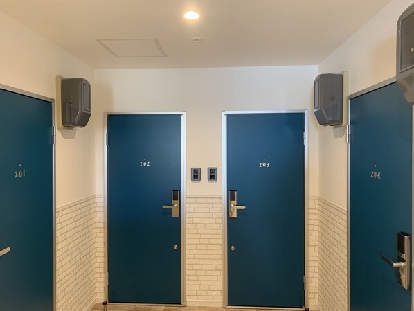 Une rangée de quatre portes bleues, portant les numéros 201, 202, 203 et 204, chacune munie d’une poignée et d’une serrure.