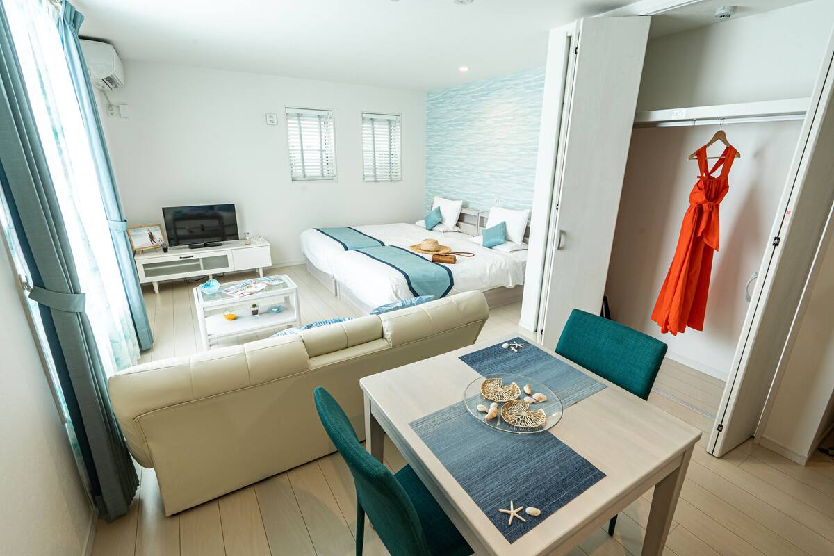 Una moderna camera d'hotel con divano, tavolo da pranzo, televisione, letto e armadio.