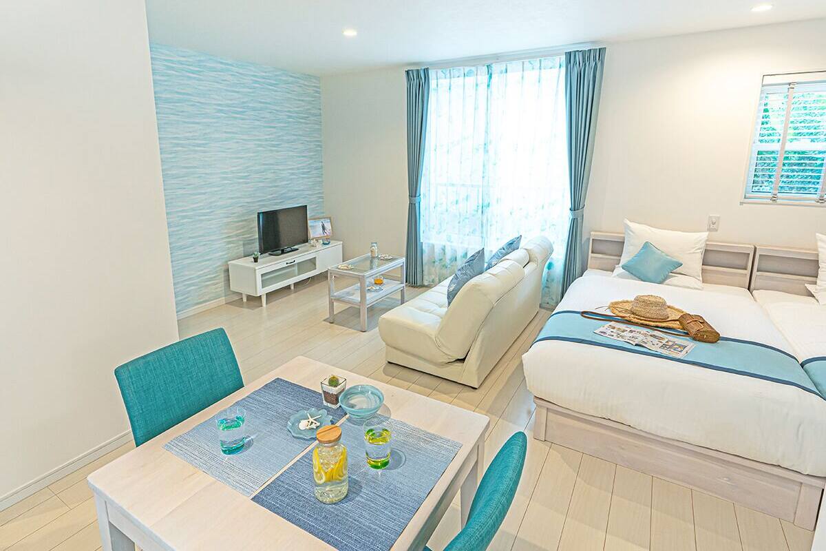 Una moderna camera d'albergo con un letto, un divano, un tavolo da pranzo con sedie, una TV e una finestra con tende.
