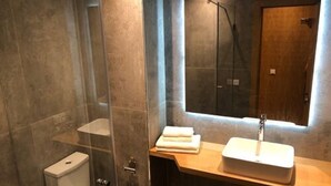 A modern bathroom with a glass-enclosed shower, a wooden vanity with a sink, and a large mirror. - Vision immo (Saint-Ouen)