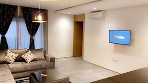 A modern living room with a sofa, a coffee table, and a flat-screen TV mounted on the wall. - Vision immo (Saint-Ouen)