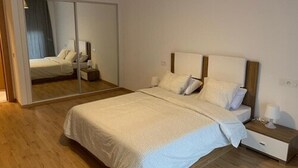 A bedroom with a bed, bedside table, and a mirror. - Vision immo (Saint-Ouen)