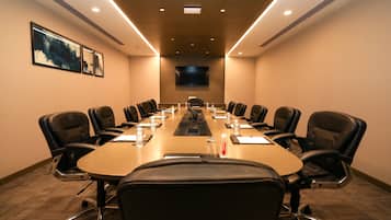 A conference room with a long table, black chairs, and a flat-screen TV on the wall.