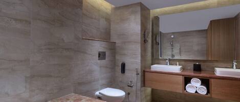 A modern bathroom with a marble bathtub, wooden vanity, and a large mirror.