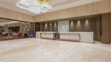 A spacious lobby with a marble floor, a reception desk, and a decorative chandelier.