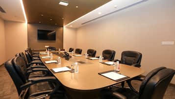 A conference room with a long table, multiple chairs, water bottles, and a flat-screen TV on the wall.