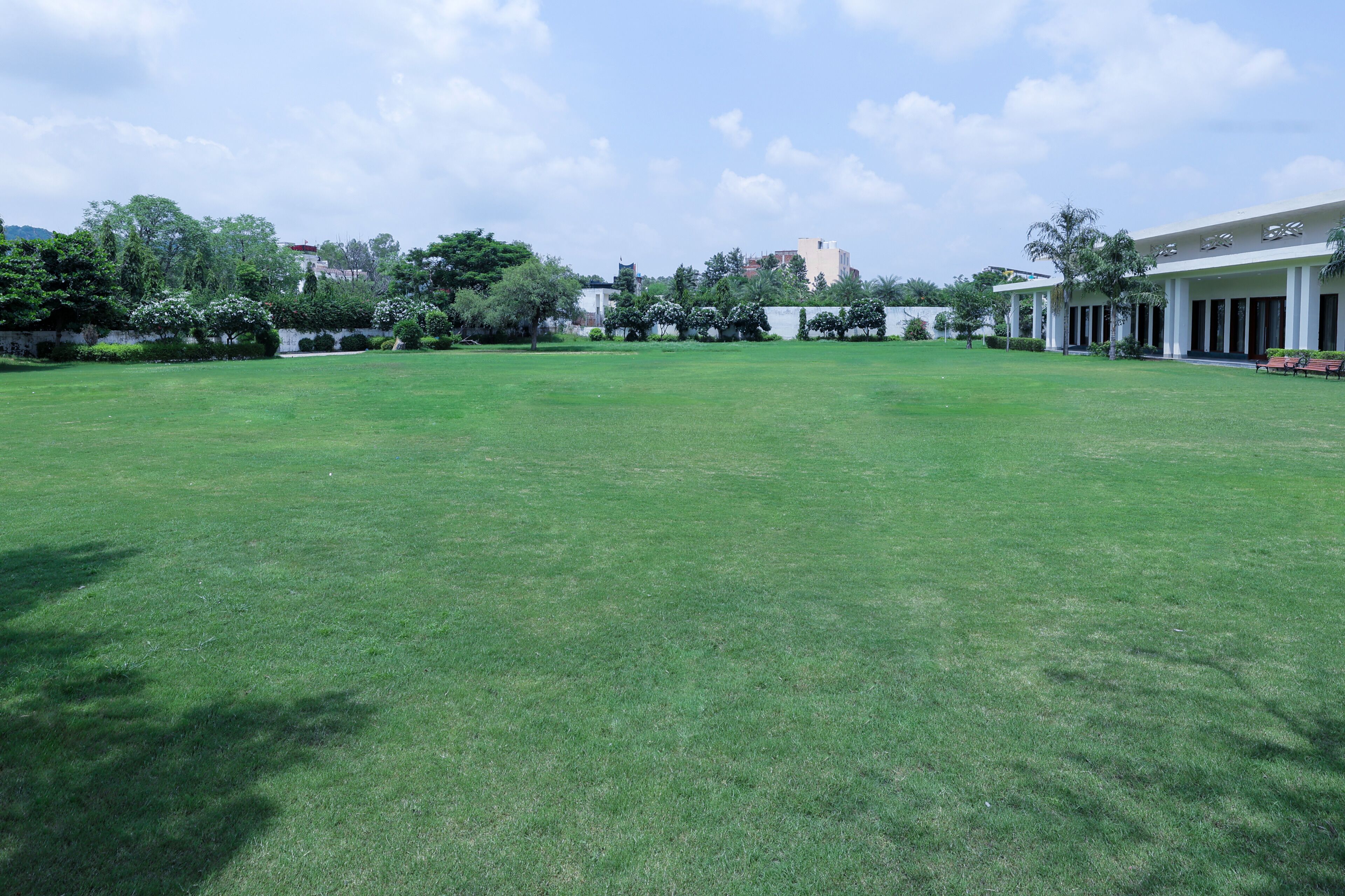 A large, open grassy area with a building featuring a covered walkway and columns.