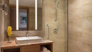 Une salle de bain moderne avec une douche à parois de verre, un grand miroir et un plan de toilette en marbre.
