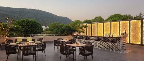 An outdoor seating area with tables and chairs, a bar, and a decorative wall.