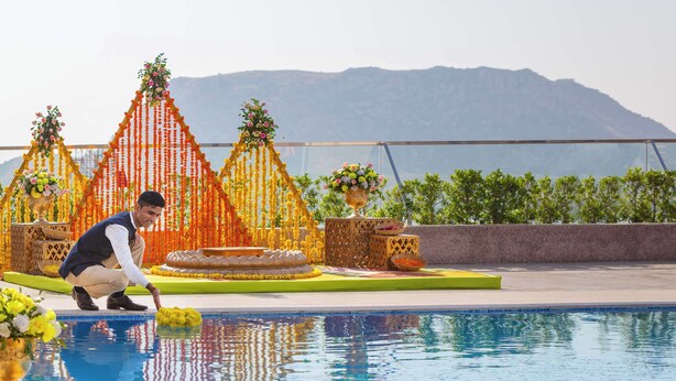 A pool area with decorative flower arrangements and a mountainous backdrop. - Doubletree by Hilton Jaipur Amer (Amer)