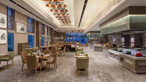 A spacious dining area with multiple tables and chairs, a long counter with food display, and a ceiling with hanging lights. - Doubletree by Hilton Jaipur Amer (Amer)