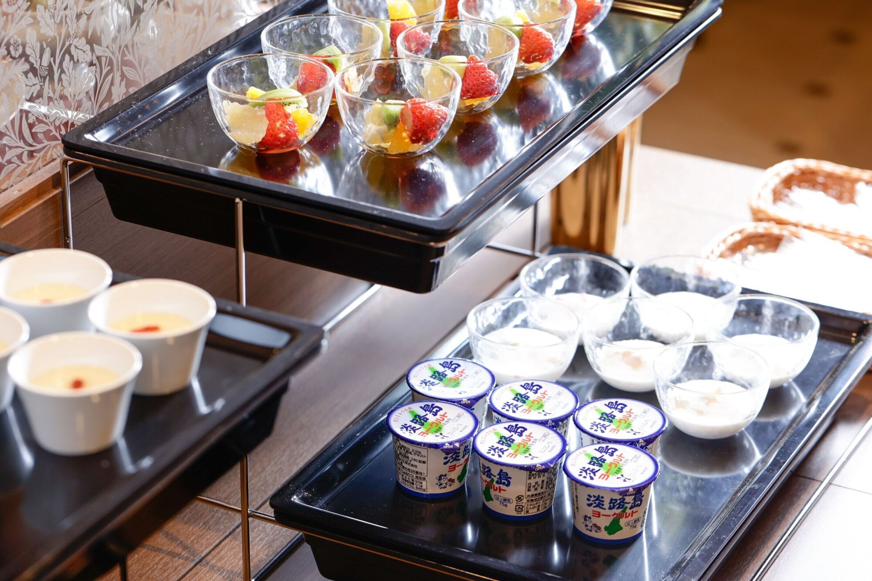 Una mesa de buffet con diversos alimentos, incluyendo ensaladas de frutas y recipientes de yogur.