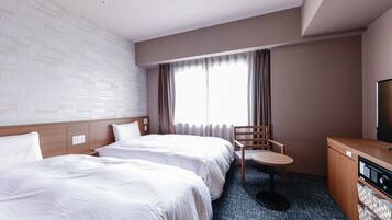 Une chambre d’hôtel avec deux lits, une petite table, une chaise, un téléviseur et une kitchenette.