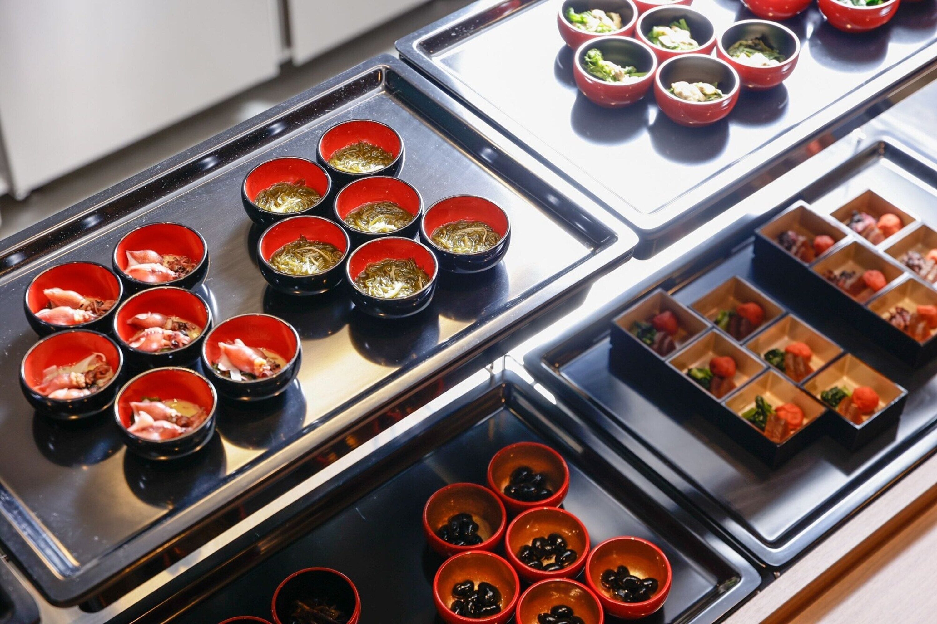 Un buffet proposant divers plats présentés dans des bols rouges et noirs.