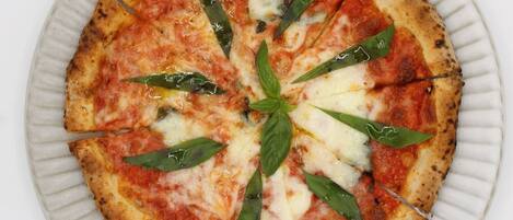 A pizza on a white plate with a ribbed edge.