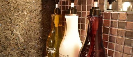 Tres botellas de acondicionador sobre una encimera con salpicadero de azulejos.