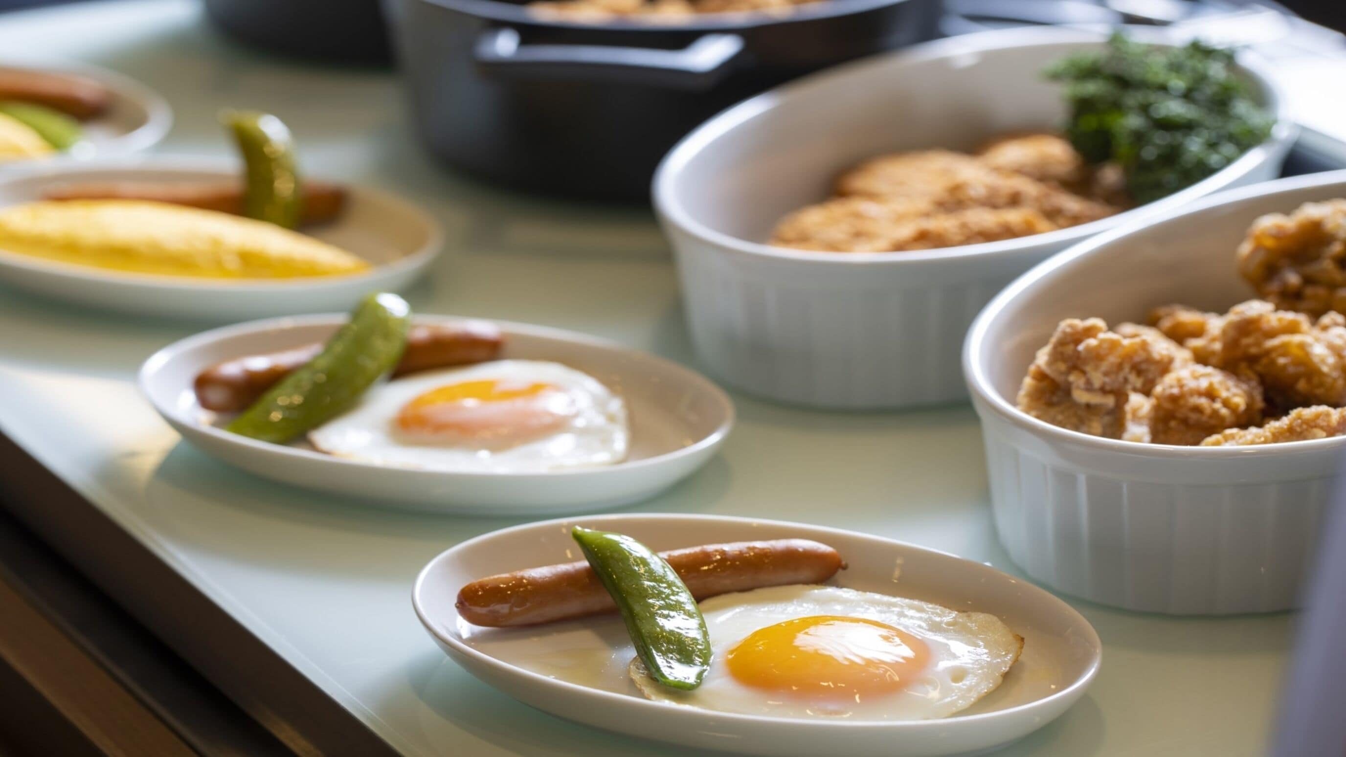 A breakfast buffet with various dishes including eggs, sausages, and pastries.