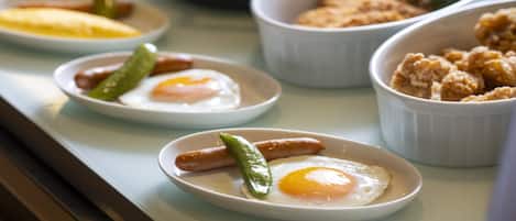 A breakfast buffet with various dishes including eggs, sausages, and pastries.