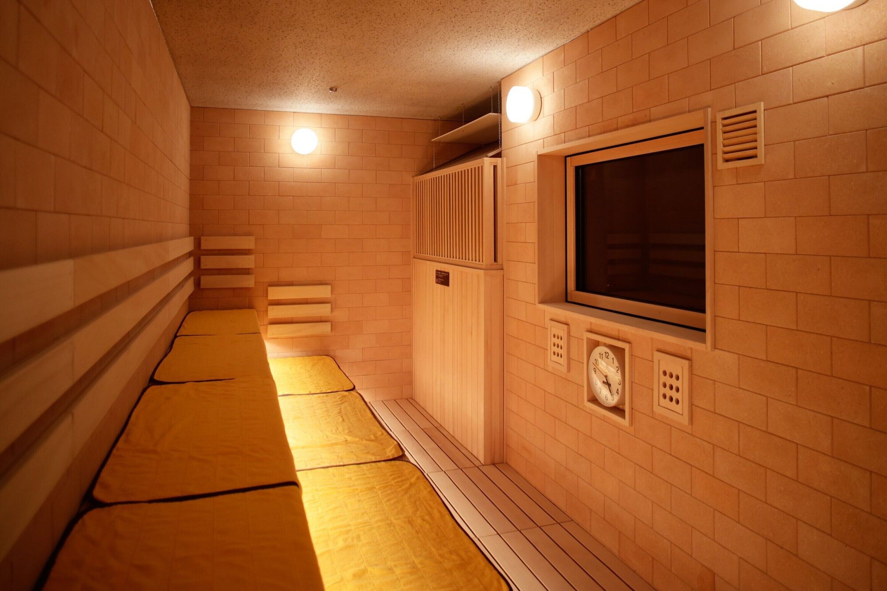 Una sala de sauna con bancos de madera, un ventanal grande y un calentador fijado a la pared.
