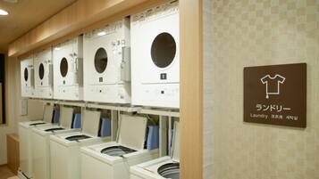 A row of front-loading washing machines in a laundromat with a sign indicating the location.