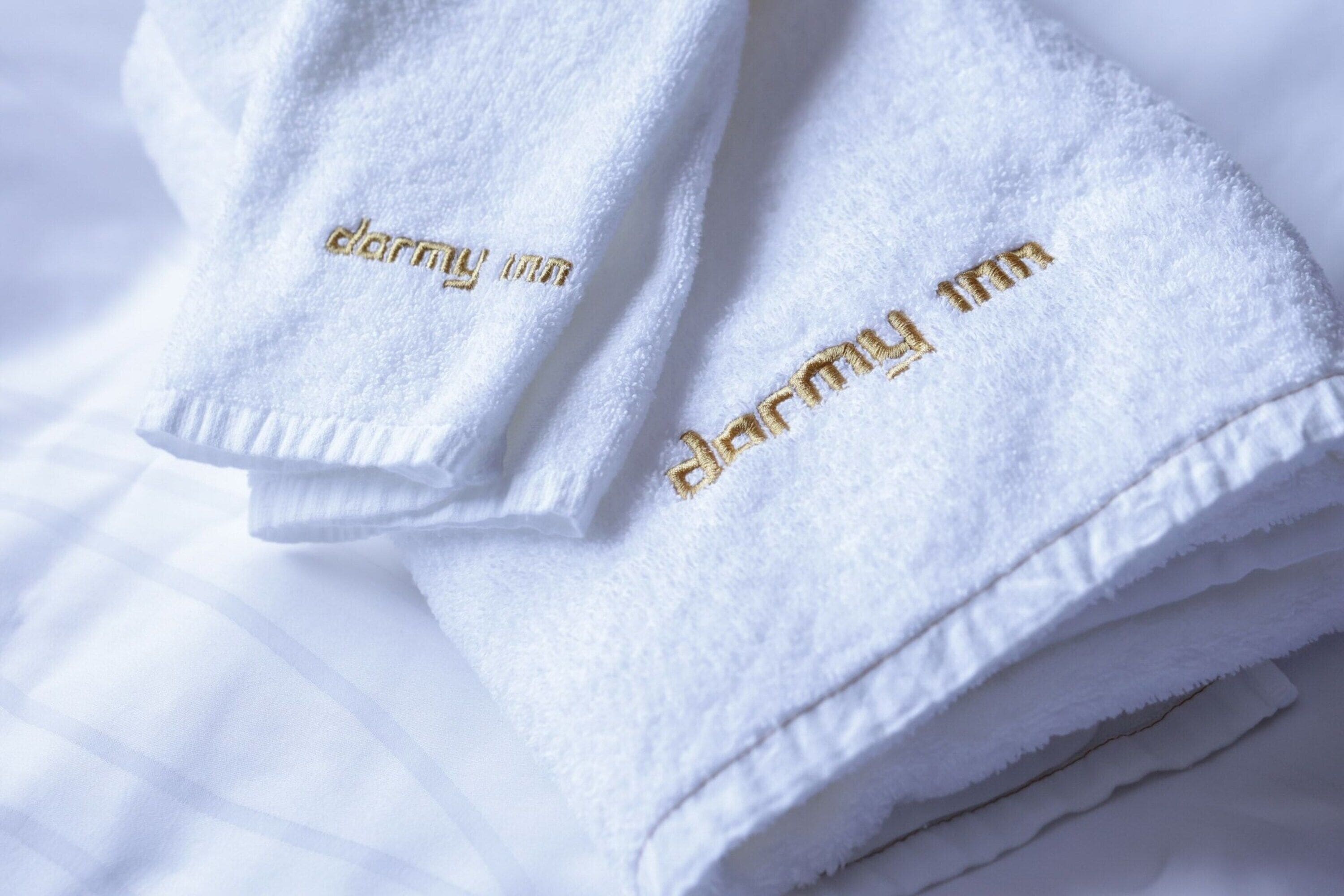 A stack of white towels with embroidered text.