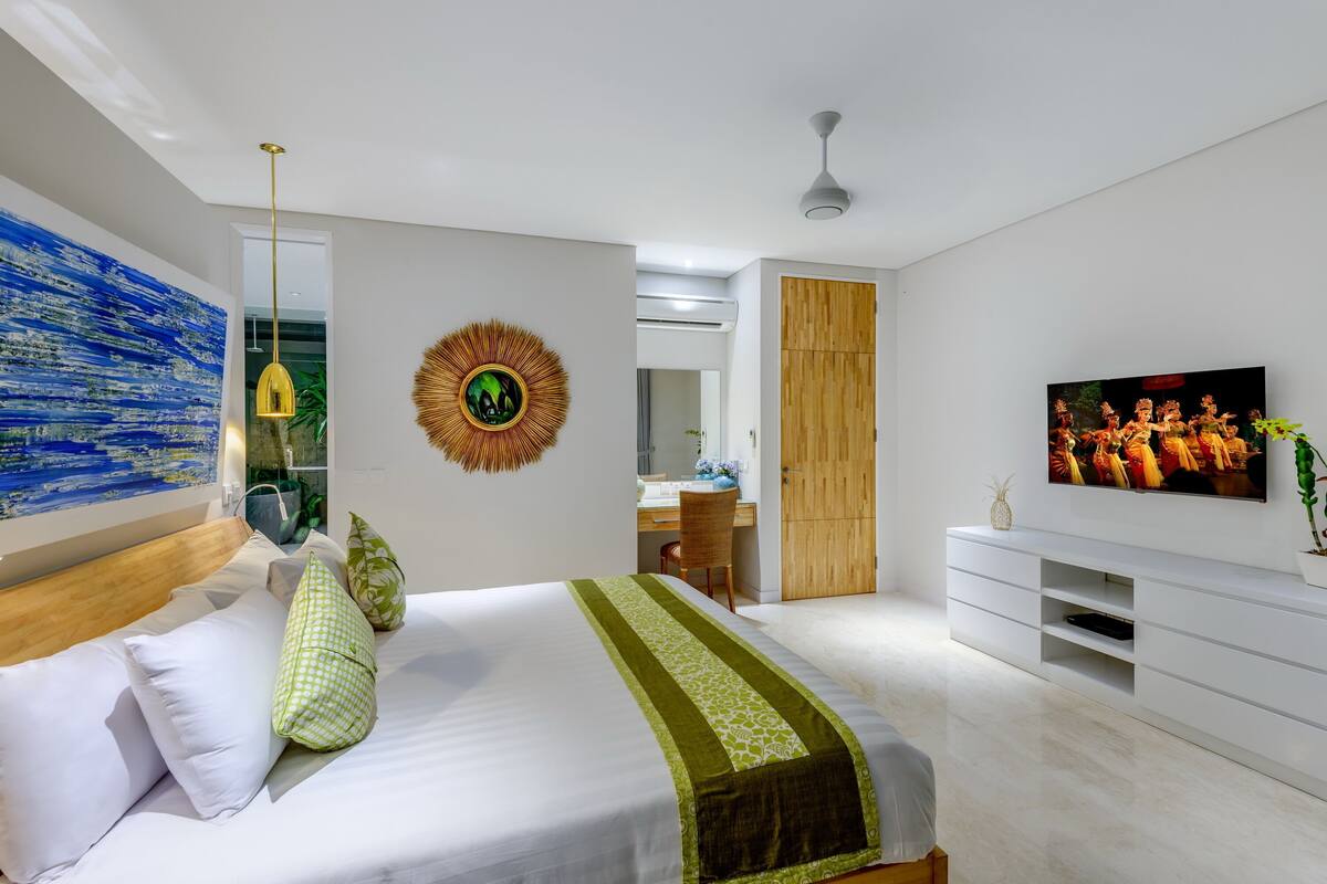 A modern bedroom with a bed, a TV, a desk, and a wardrobe.