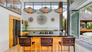 Een moderne keuken met een groot eiland, drie hanglampen en een decoratief wandkunstwerk.