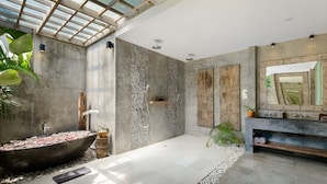 Ein modernes Badezimmer mit einer großzügigen, freistehenden Badewanne, einer großräumigen Dusche und einem Waschtisch mit Spiegel.