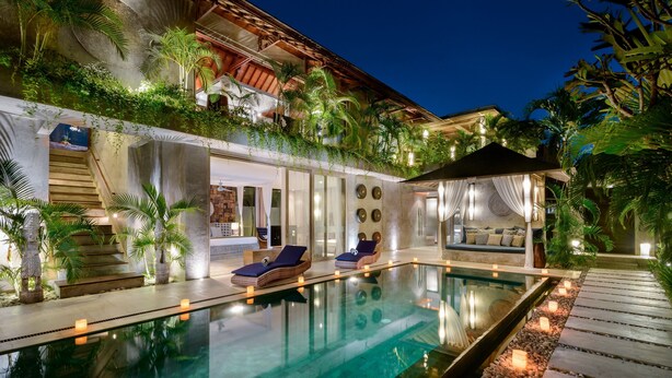 Ein luxuriöser Poolbereich mit klarem Pool, Liegestühlen und einer überdachten Sitzgelegenheit.