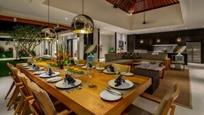 A modern dining area with a wooden table set for a meal, surrounded by chairs. - Villa The Maya (Canggu)