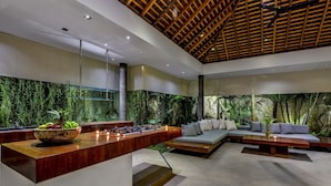 Una cocina moderna con encimera de madera, un frutero y una estufa integrada. Hay una zona de estar con un sofá y una mesa de centro.
