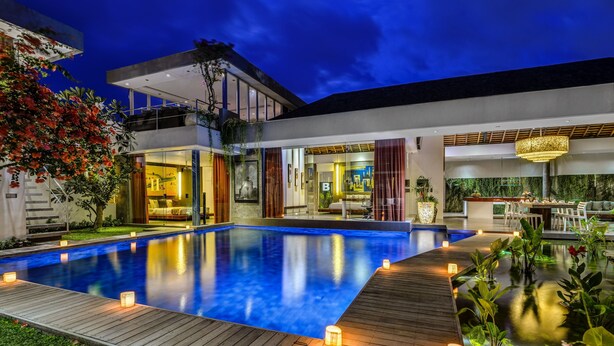 Una casa moderna con piscina, terraza de madera y espacios de estar integrados, tanto interiores como exteriores.