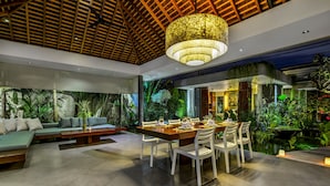 Un espacio interior moderno con comedor, asientos y vistas a un jardín exuberante.