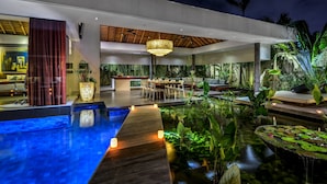 Un hotel moderno con piscina, zona de comedor y abundante vegetación.