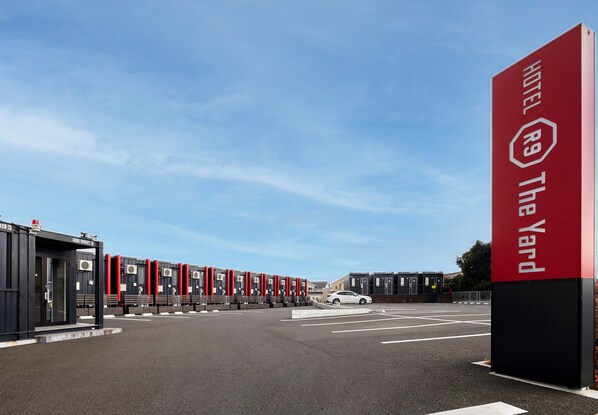 L’entrée d’un hôtel, avec une enseigne rouge, de nombreuses chambres et un espace de stationnement.