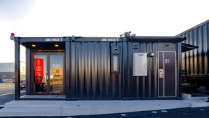 A modern building with a metal exterior, a glass door entrance, and a sign indicating a hotel. - HOTEL R9 The Yard Ota (Ota)