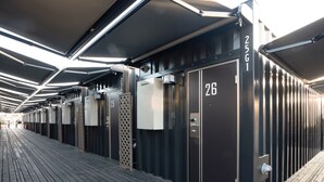 A row of hotel rooms with numbers 25 and 26, featuring a modern design with metal doors and a wooden deck outside. - HOTEL R9 The Yard Ota (Ota)