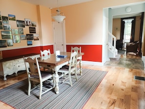 A dining room with a wooden table and chairs, a chandelier, and a wall decorated with framed pictures.