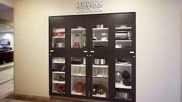 A LENDING LOCKER with multiple compartments for storage, including shelves for kitchenware and sports equipment.