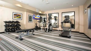 Un gimnasio de hotel con cinta de correr, elíptica y press de banca.