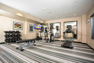Un gimnasio de hotel con cinta de correr, elíptica y press de banca.