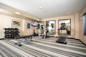 A hotel fitness room with a treadmill, elliptical, and bench press. - Candlewood Suites Jacksonville - Mayport (Atlantic Beach)