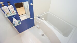 Ein Badezimmer mit einer Badewanne, einer blauen Wand und Regalen mit Pflegeprodukten.