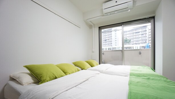 Ein Schlafzimmer mit einem Bett, Kissen und einem Fenster mit Blick auf ein Gebäude.