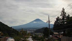 A mountain with a conical shape, surrounded by residential buildings and vegetation. - Dot Glamping Fujisan (Fujikawaguchiko)